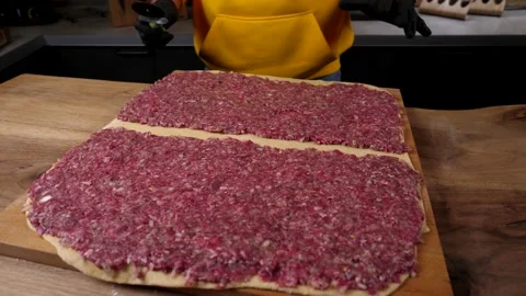 A man prepares a roll of dough stuffed with meat, onions and spices Stock Footage 136830081