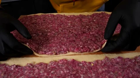 A man prepares a roll of dough stuffed with meat, onions and spices Stock Footage 136830164