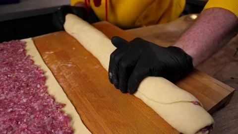 A man prepares a roll of dough stuffed with meat, onions and spices Stock Footage 136830304