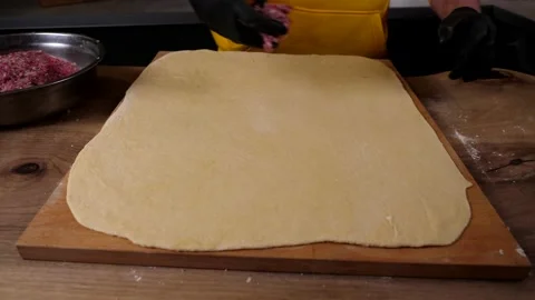 A man prepares a roll of dough stuffed with meat, onions and spices Stock Footage 136830518