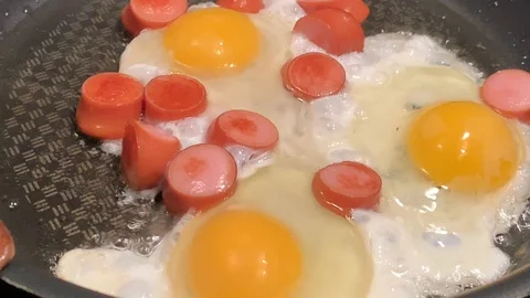 A man prepares scrambled eggs with sausage for breakfast 库存影片 104764071