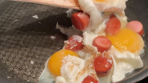 A man prepares scrambled eggs with sausage for breakfast Stock Footage 104796173