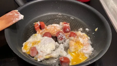 A man prepares scrambled eggs with sausage for breakfast Stock-Footage 104799628