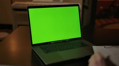 A man prepares to take notes learning online on a laptop with a green screen Stock Footage 145169718