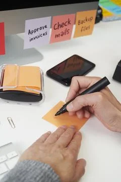A man prepares to write a task note at a desk 写真素材