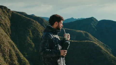 Man preparing and drinking traditional mate outdoors, surrounded by green Stock Footage 328281565