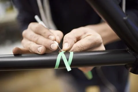 Man preparing a bike frame for a custom painting design using a scalpel and.. Stock Photos