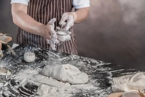 Man preparing buns at table in bakery Фото