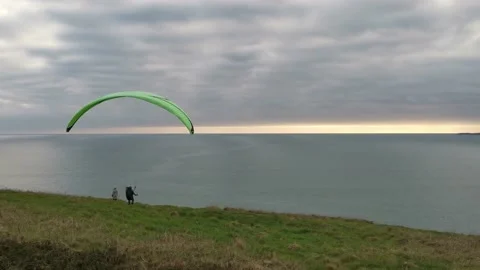 A man is preparing to catch a wind with his paraglide while woman is Stock Footage 150153266