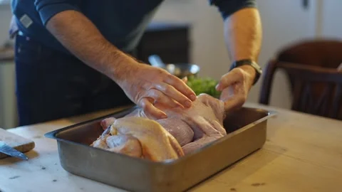A man is preparing a chicken in a pan Stock Footage 295367578
