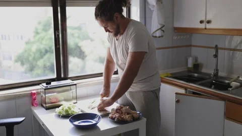 Man preparing chicken in a small kitchen Stock Footage 311182626