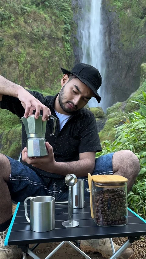 Man Preparing Coffee with Moka Pot by Waterfall in Jungle Vertical Stock Footage 323907368