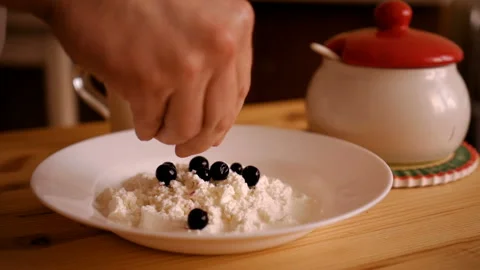 The man is preparing a delicious curd dessert with currant berries. Hands of Stock Footage 93371739