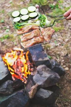 Man preparing dinner on campfire, adventure lifestyle camping vacation concep Stock Photos