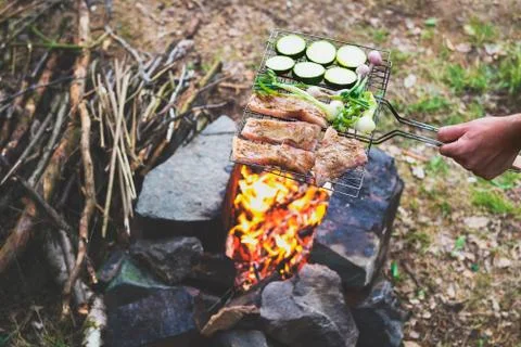 Man preparing dinner on campfire, adventure lifestyle camping vacation concep Stock Photos