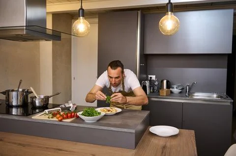 A man preparing dinner in home kitchen. Selective focus on hands holding gree Fotos de archivo