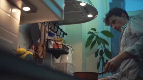 Man preparing dinner in pan on stove in kitchen. stirs wooden spoon Stock Footage 83086917