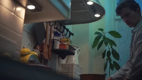 Man preparing dinner in pot on stove in kitchen. stirs wooden spoon Stock Footage 83086674