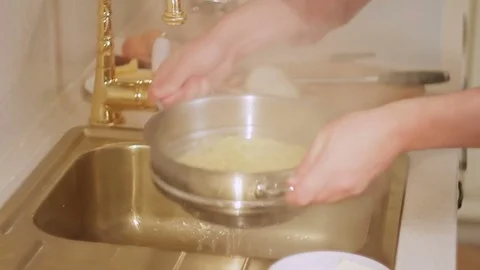 The man is preparing dinner, washing pasta with water under the tap Stock Footage 81423524
