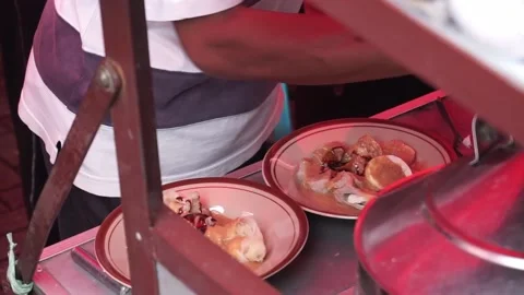 A man preparing a dish called 'Batagor' to customer on the street of Malang. Stock Footage 219465285