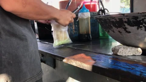 A man preparing a dish called 'batagor' to customer on the street Stock Footage 249915126