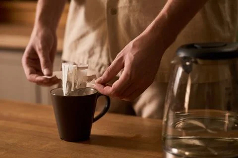 Man Preparing Drip Bag Coffee in Cup at Home Kitchen Fotos de archivo