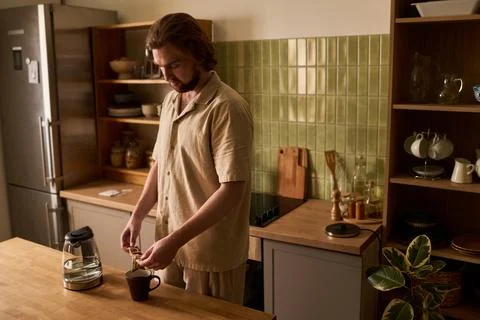 Man Preparing Drip Coffee Bag in Kitchen during Morning Routine Fotos de archivo