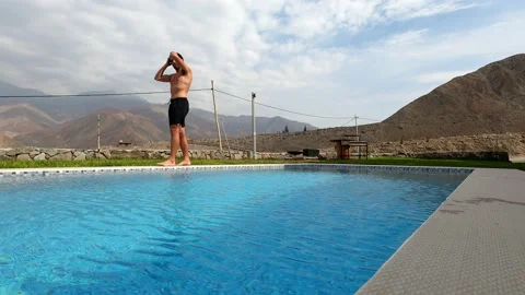 A man preparing to enter the swimming pool with a beautiful view of mountains an 库存影片 199541319