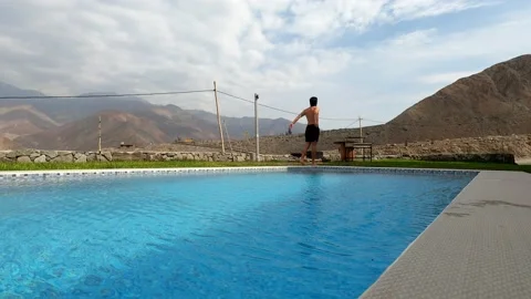 A man preparing to enter the swimming pool with a beautiful view of mountains an Stock Footage 199542105