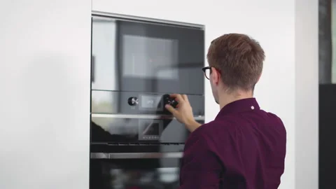 Man preparing food in the kitchen using microwave. Realtime Stock Footage 225533718