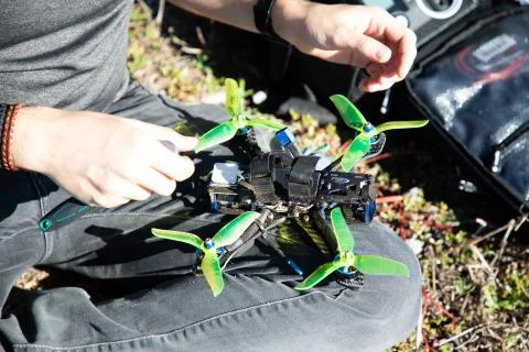 Man preparing fpv racing drone on lap with green propellers Stock Photos