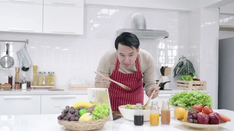 Man preparing a fresh salad in a bright kitchen Stock Footage 186918443