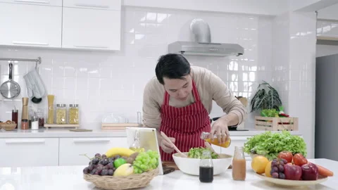 Man preparing a fresh salad in a bright kitchen Stock Footage 186919080