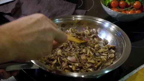 A man is preparing fried champignon mushrooms with onions in an iron frying.. Stock Footage 252067435