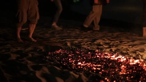 Man preparing to go over hot coals that lie on beach sand, at last runs through Stock Footage 115930563