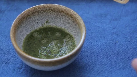 Man preparing green tea matcha in a bowl on blue surface Video stock 105785682