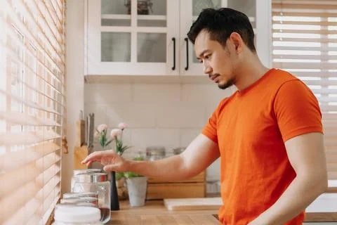 Man preparing his easy breakfast in the kitchen in warm light morning. Stock Photos