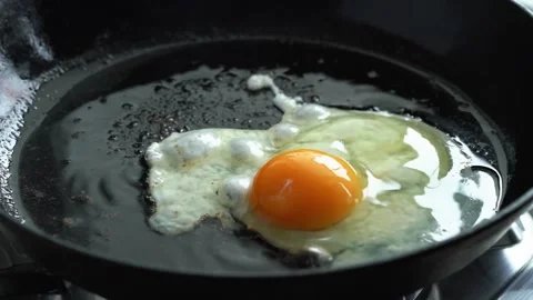 Man preparing keto meal eggs frying on hot cast iron frying pan, three fried Stock Footage 150882515