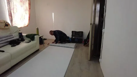 Man preparing large roll of paper in living room, measuring and cutting with too Video stock 332514786