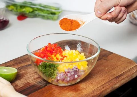 Man preparing mango salsa, adding spices Stock Photos
