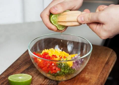 Man preparing mango salsa, squeezing lime juice Stock Photos