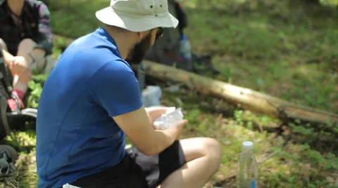 A man preparing a meal in a pot on a gas burner in the forest. Sitting on the Video stock 64529641