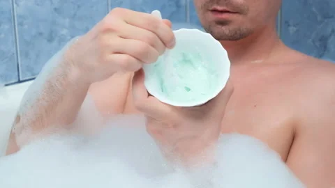 Man is preparing mixing alginate mask lying in bathroom at home, closeup bowl. Stock Footage 154032639