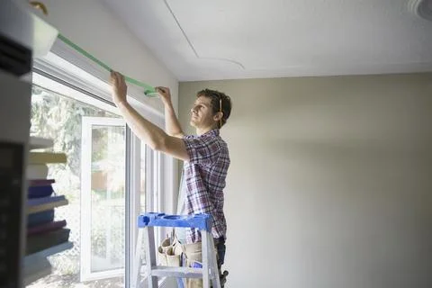 Man preparing to paint by taping window casing Stock Photos