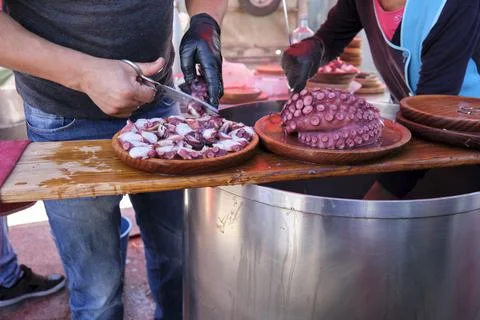 Man preparing a portion of the dish the traditional Galician octopus recipe. Stock Photos