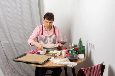 A man is preparing for a pre-Christmas dinner by baking chicken and potatoes. Stock Photos