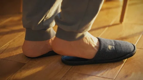 Man preparing to put on slippers by the warm sunlight in a cozy indoor setti Stock Footage 323866804