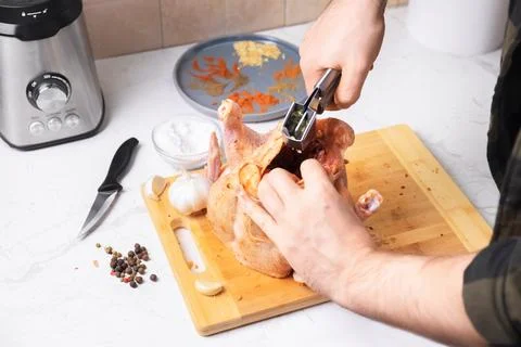 Man preparing raw chicken for roasting by squeezing fresh garlic inside. Ma.. Stock Photos