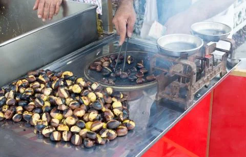 Man preparing roasted chestnuts, cooking outdoors. Stock Photos