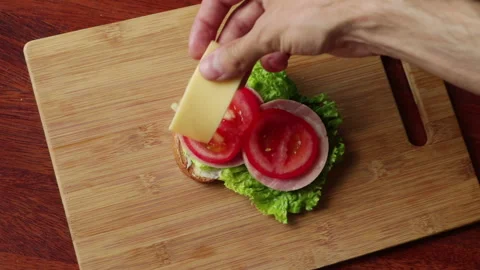Man preparing sandwich with ham cheese salad tomato cucumder onion top view Stock Footage 135885377